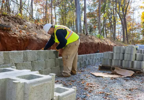 A worker is seen building a foundation on a construction site. Basement Systems Waterproofing & Foundation is a foundation contractor in Pekin IL.