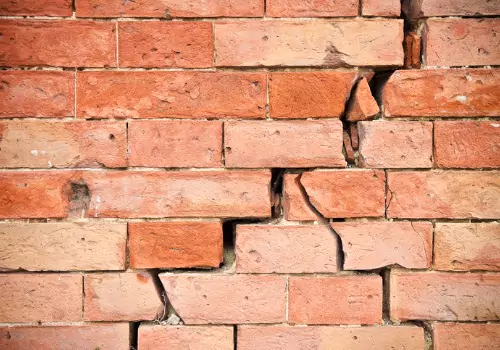A damaged brick wall is seen. Basement Systems Waterproofing & Foundation performs Foundation Crack Repair in East Peoria IL.