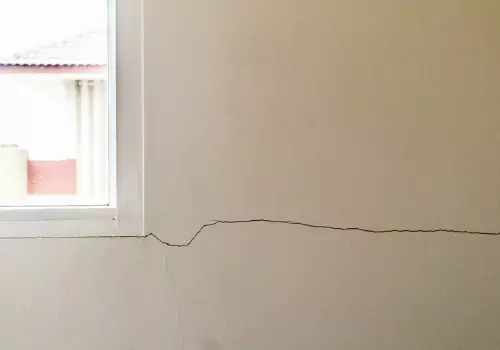 A window with a cracked wall, a sign of a home needing foundation repair in Peoria IL